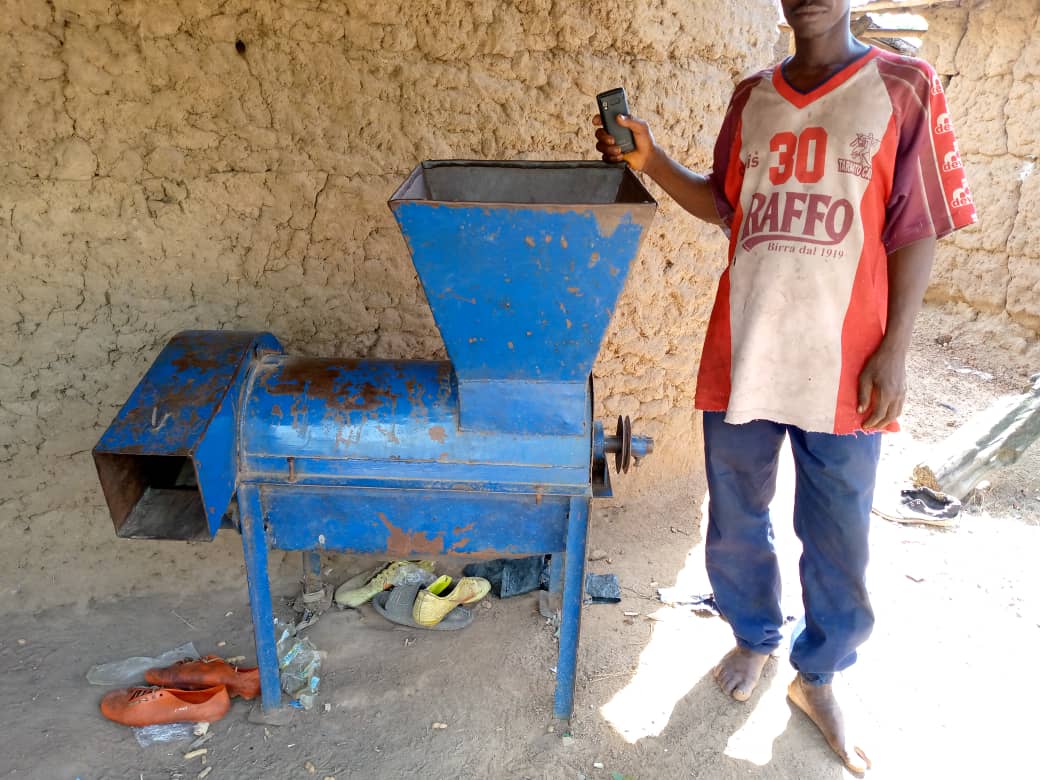 Un homme pose devant une machine à transformer le riz, au Togo, en Afrique