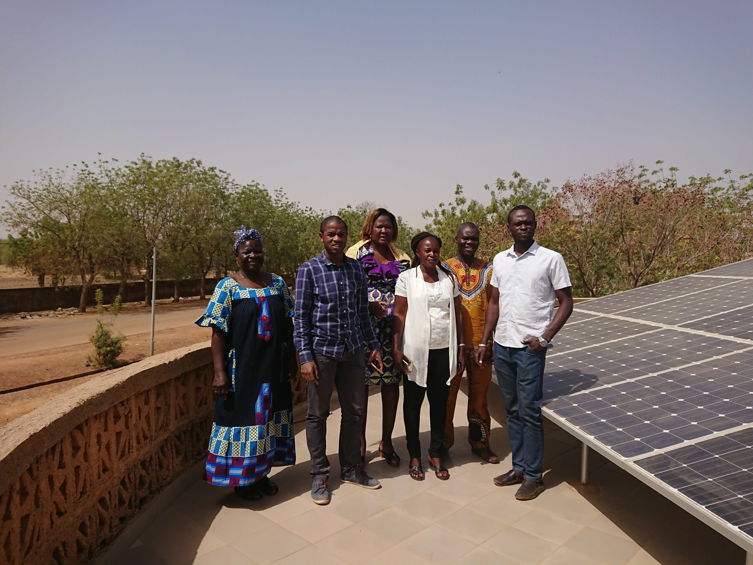 Bubacar Diallo de Benoo avec 5 membres d’A2N, posant devant des panneaux solaires au Burkina Faso.