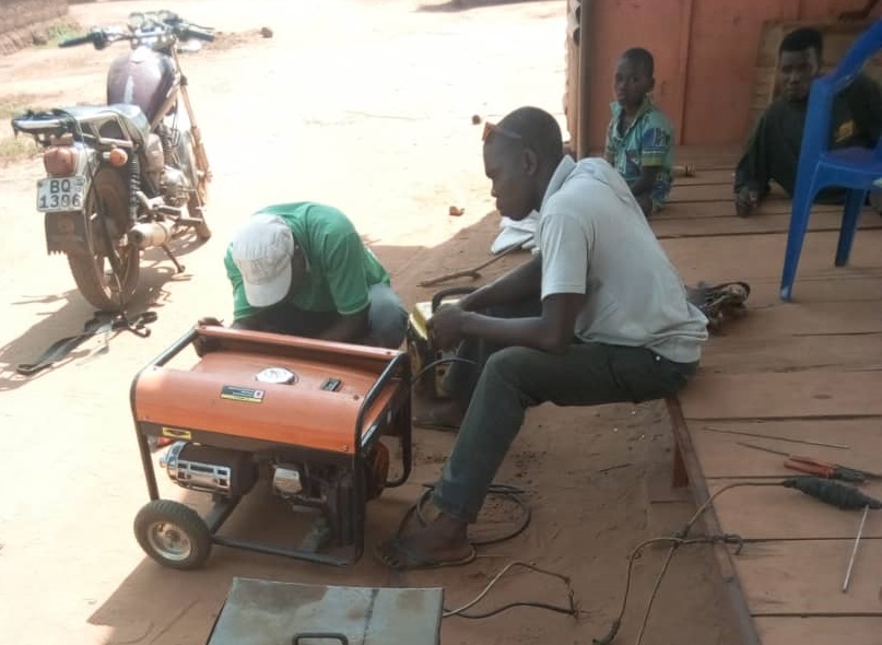 Un homme répare un générateur diesel en Afrique